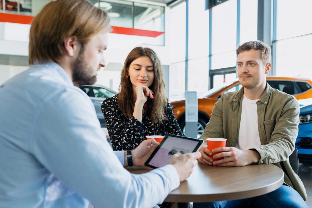 A man going over the dealership payment workflow with customers as he is about to accept their down payment.