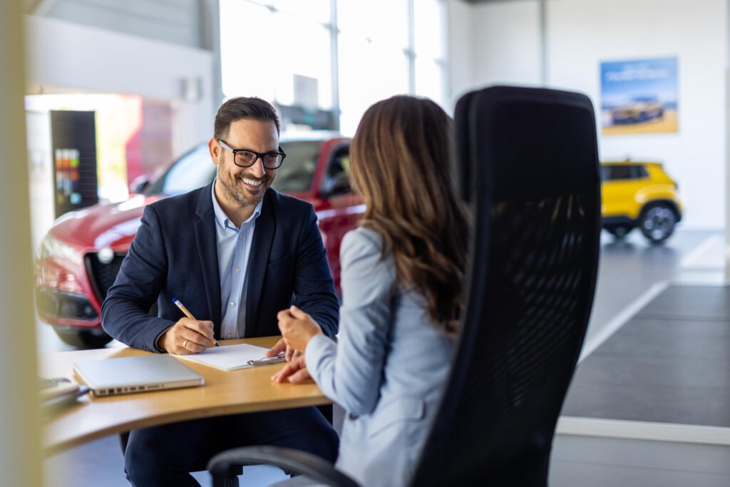 Transparent pricing: a young woman signing car purchase documents