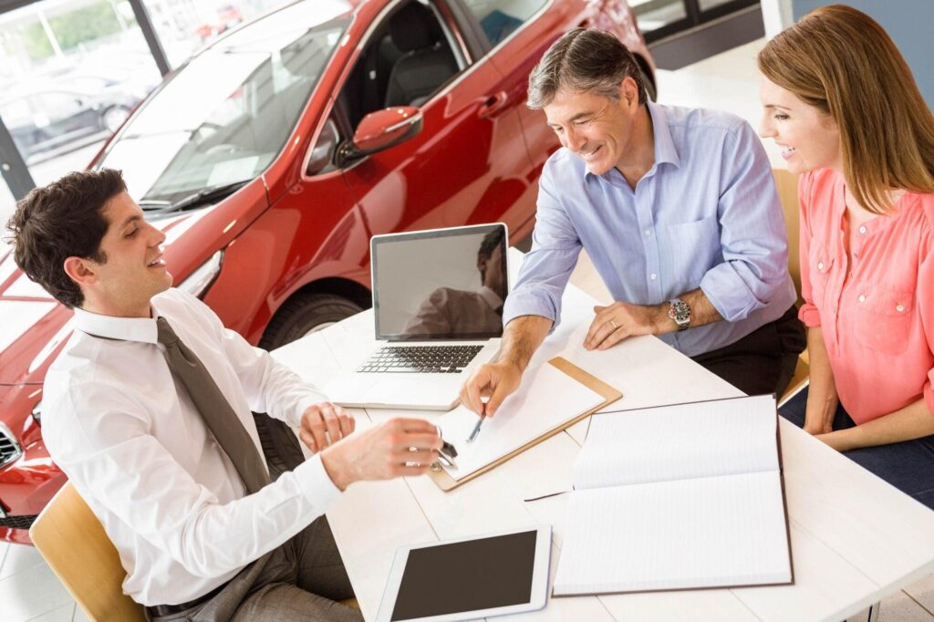 Finance team sits at table with customers going over purchase agreement to ensure seamless payment reconciliation.